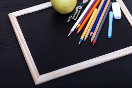 Back to school concept, colored pencils on black table, multicolored stationery accessories for educator teaching kid drawing on empty wooden desk, creative education background, top view, copy spaceの写真素材