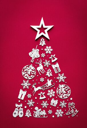 Merry christmas tree concept made of white 2020 happy new year decorated wooden toys star on top view isolated on red background table minimal flat lay, merry xmas winter holiday party, verticalの写真素材