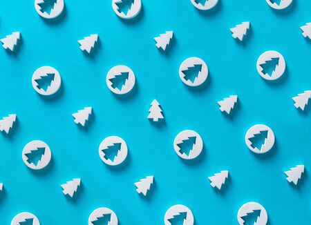 Merry Christmas background concept, winter holidays happy new year white trees decorations minimal pattern creative design photo on blue pastel table, flat lay, copy space, top close up view aboveの写真素材