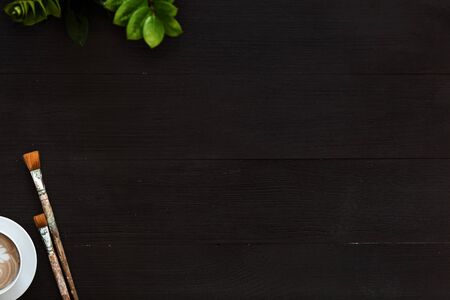 Creative art wooden blank black background with coffee and paintbrushes on artistic table, artist painter brushes on wood desk top view from above, creativity lesson, teaching painting, flat layの写真素材