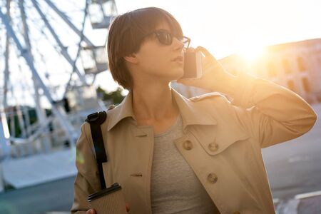 Fashion teen girl talking on mobile phone walking on city street.の写真素材