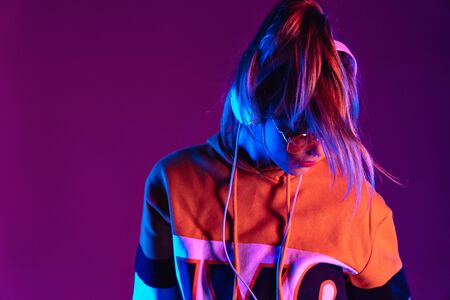 Teen girl wear headphones listen music dancing standing at purple background.