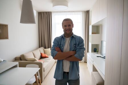 Portrait of young man in modern studio apartment look at camera.の写真素材