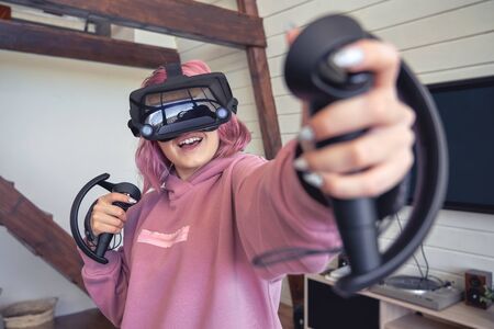 Excited teen hipster girl playing virtual reality video game wear vr goggles.の写真素材