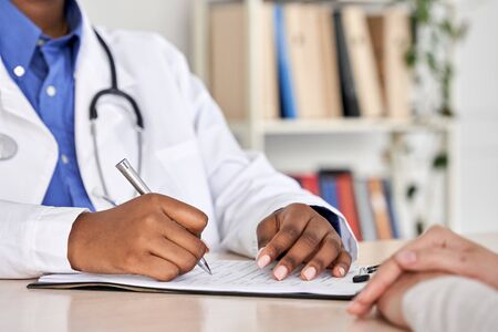 African black doctor consult woman patient filling medical form at appointment.の写真素材