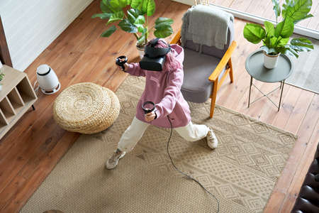 Teen girl pink hair wear vr goggles play virtual reality game at home, top view.
