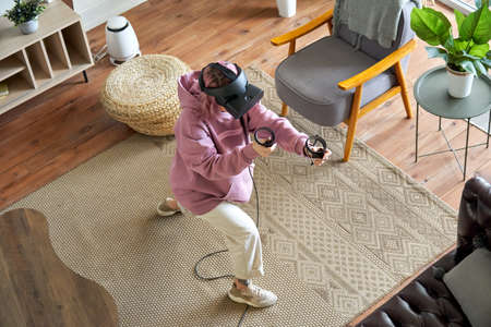 Teen girl wear vr headset play virtual reality modern game at home, top view.