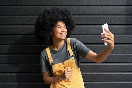 Happy African girl blogger holding smartphone shooting vlog or video calling.の写真素材