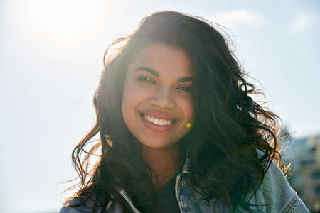 Smiling attractive African girl dental smile looking at camera outdoor headshot.