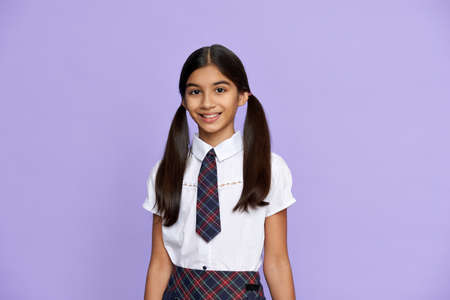 Smiling indian kid girl wear school uniform stand on lilac background, portrait.の写真素材