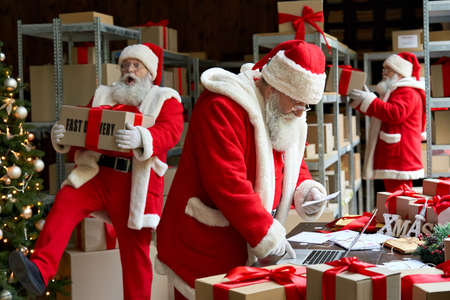 Many Santa Clauses packing presents gift boxes preparing fast xmas delivery.