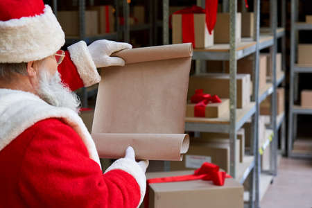 Santa Claus reading blank empty wish list in workshop gifts warehouse.の写真素材