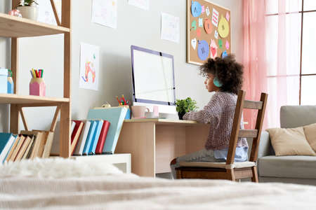 African school kid girl wearing headphones distance learning at home.