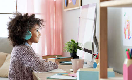 African american kid girl online learning on computer at home.