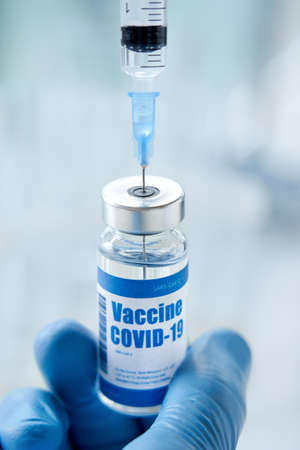 Male doctor or scientist hand holding syringe taking covid 19 vaccine from vial.の写真素材