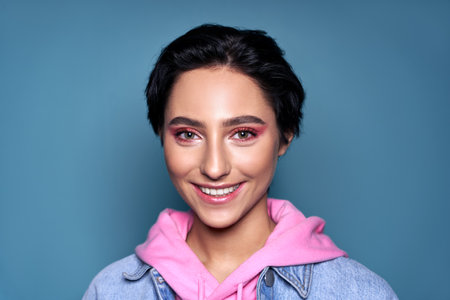 Happy cool gen z teen girl looking at camera on blue background. Portraitの写真素材