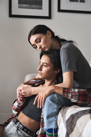 Young affectionate lesbian couple in love hugging at home.の写真素材