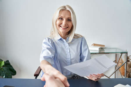 Smiling hr manager, employer shaking hand hiring employee looking at camera.の写真素材