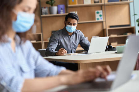 Indian business man wearing face mask working on laptop in office coworking.の写真素材