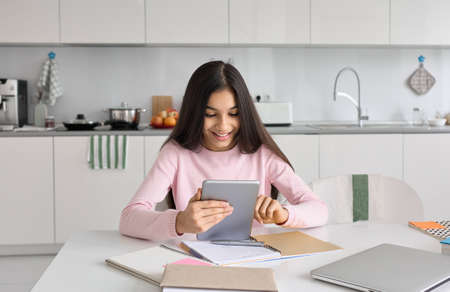 Indian school girl distance learning online at home using tablet.