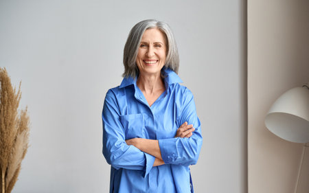 Senior laughing 60s woman portrait indoors looking at camera.