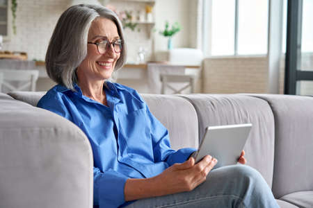 Senior happy older woman at home at video meeting with family doctor.