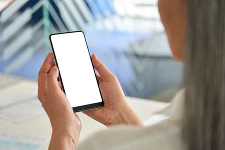 Female older businesswomans hands holding cell phone with empty screen.