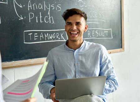 Young happy indian latin man student with laptop laughing at office meeting.の写真素材
