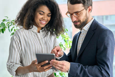 Mentor ceo holding tablet device and female manager discuss project in office.の写真素材