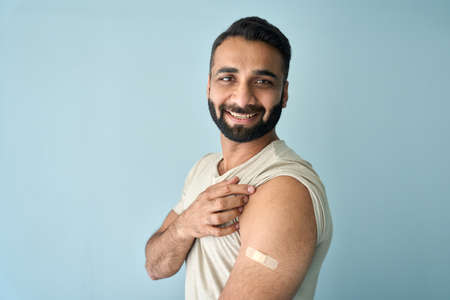 Portrait of young Indian man after covid19 vaccine with plaster on shoulder.