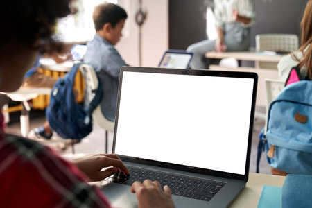 African American school kid girl using laptop computer with white mockup screen.の写真素材