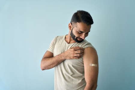 Happy Indian man showing bandage plaster after getting vaccination.の写真素材