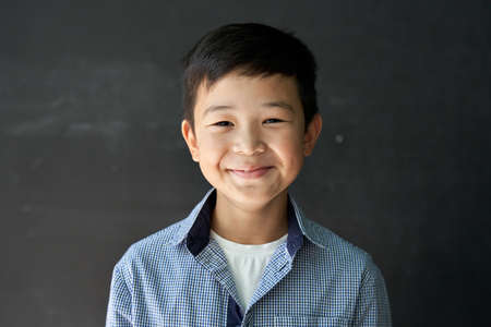 Happy Asian kid boy school student looking at camera at blackboard background.の写真素材