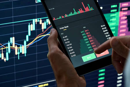 Crypto investor holding finger on buy sell button executing stock trading order.