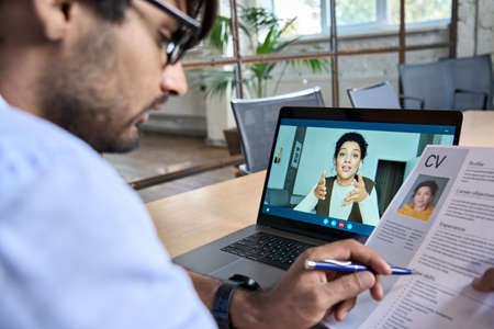 Indian human resource manager holding cv having virtual job interview.の写真素材