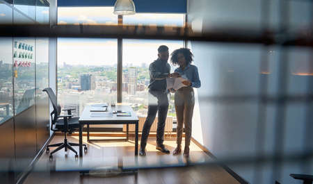 Multiracial colleagues standing discussing report paperwork in modern office.の写真素材