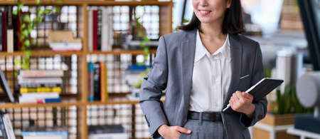 Young business woman teacher wearing suit holding digital tablet, banner.の写真素材