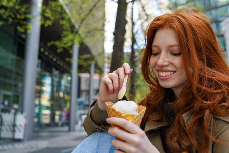 Smiling cool teen hipster girl eating ice cream on big city urban street.