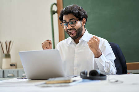 Excited indian business man looking at laptop celebrating win with yes gesture.の写真素材