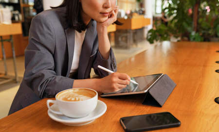 Young business woman using digital tablet working sitting in cafe.の写真素材