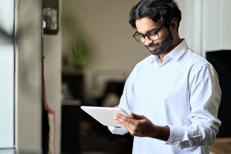 Smiling young indian business man employee using digital tablet.の写真素材