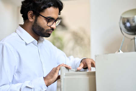 Indian business man searching corporate documents in archive drawer.