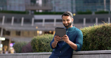 Professional indian business man using digital tablet in night city park.
