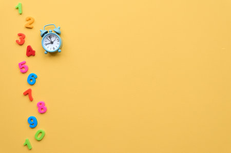 Small alarm clock and figures on yellow background, flat lay, top view.の写真素材