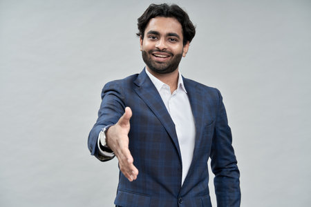 Smiling arab business man extending hand for handshake isolated on beige.
