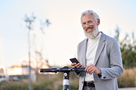 Happy old man using mobile app for bike rental renting bike in city park.の写真素材