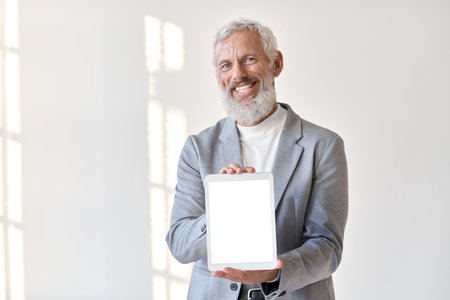 Smiling older business man showing tablet mockup screen isolated on white.の写真素材