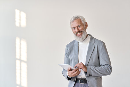 Smiling old senior business man using tablet isolated on white background.の写真素材