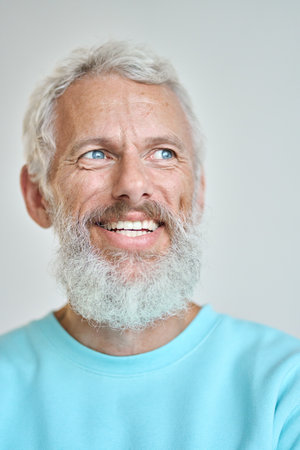 Smiling senior old man looking away dreaming isolated on white. Vertical closeupの写真素材