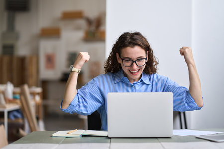 Young happy business woman student feels excited wins online looking at laptop.